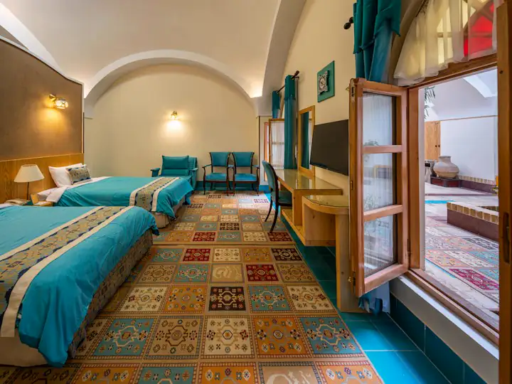 Kemerli taş tavanı ve kilim halısı olan bir otel odası